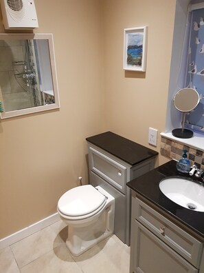Une salle de bain comprenant des toilettes, un lavabo, un miroir et une douche.