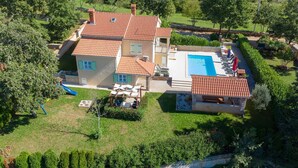 Uma casa de dois andares com piscina, área de recreação infantil e jardim.
