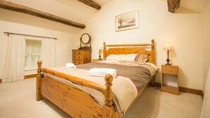 Un dormitorio con una cama de madera, una mesita de noche, una ventana con cortinas y un cuadro colgado en la pared.
