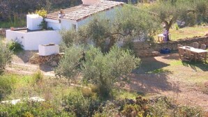 A rustic house with a tiled roof, surrounded by greenery and a stone wall. - Sun, sea, calm and space in a finca 6.5 ha, Casita Tres (El Perelló)