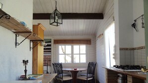 A kitchen with a dining table, chairs, a stove, and a window. - Sun, sea, calm and space in a finca 6.5 ha, Casita Tres (El Perelló)