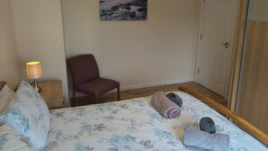 Une chambre d’hôtel avec un lit, une chaise, un tableau au mur et une porte.