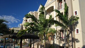 Un hôtel doté d’une piscine, de palmiers et d’un espace salon abrité.