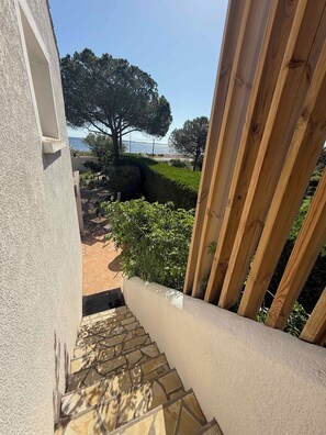 A view from a balcony with a stone staircase leading to a patio area.