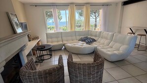 A living room with a sectional sofa, two armchairs, a coffee table, a fireplace, and large windows with a view.