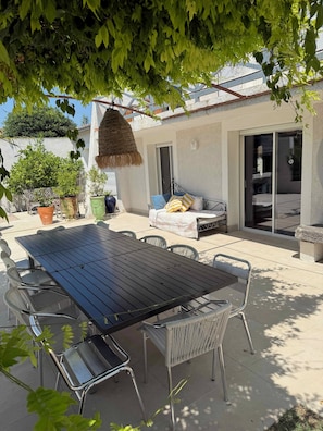 A patio with a dining table, chairs, and potted plants.