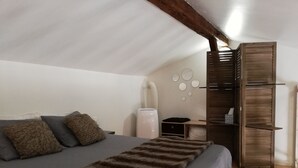 Een slaapkamer met een bed, een houten garderobe, een bureau met stoel, en een wandradiator.