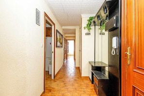 Stylish corridor with a light-colored wall, patterned tile floor, and a wooden door.