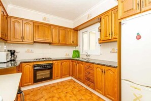 Kitchen features a stove, oven, sink, and refrigerator, with a window above the sink.