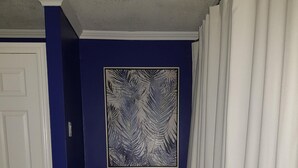 A room with a blue accent wall, a black chair with a white cushion, a beige ottoman, and a white door.