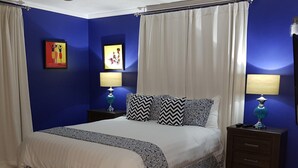 A bedroom with a bed, two nightstands, a ceiling fan, and two wall-mounted lamps.