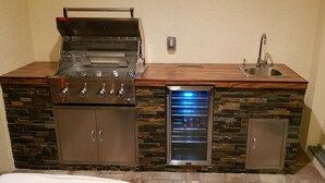 A compact kitchen with a built-in grill, a refrigerator, and a sink. - Villa Alani -- Luxurious south-facing dream villa directly on the canal / river connection (Cape Coral)