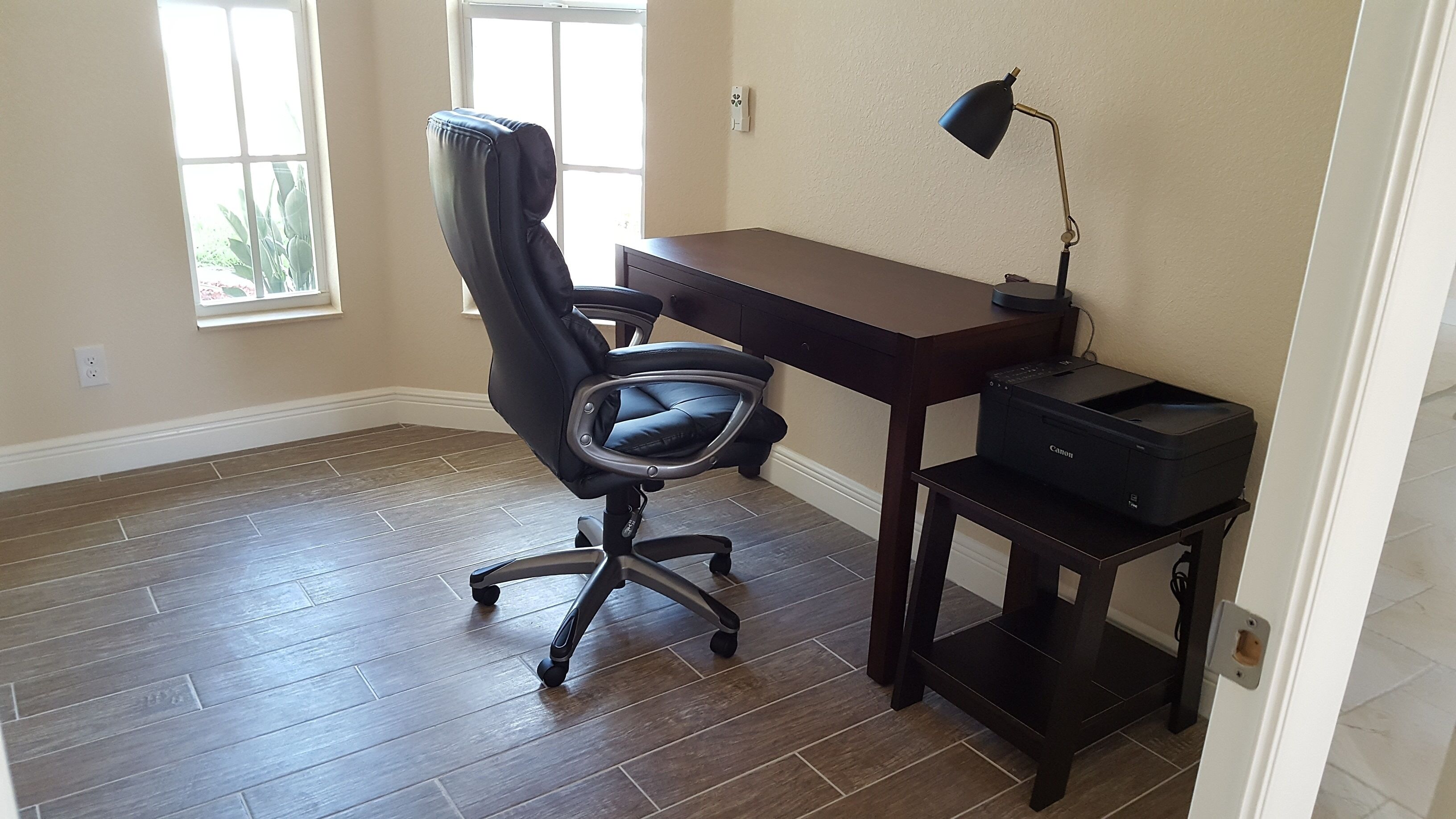 Een werkplek aan huis met een bureau, stoel en printer.