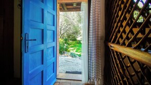 An open blue door leading to a garden with a stone pathway and greenery. - Garden Villa near Costa Smeralda (Olbia)
