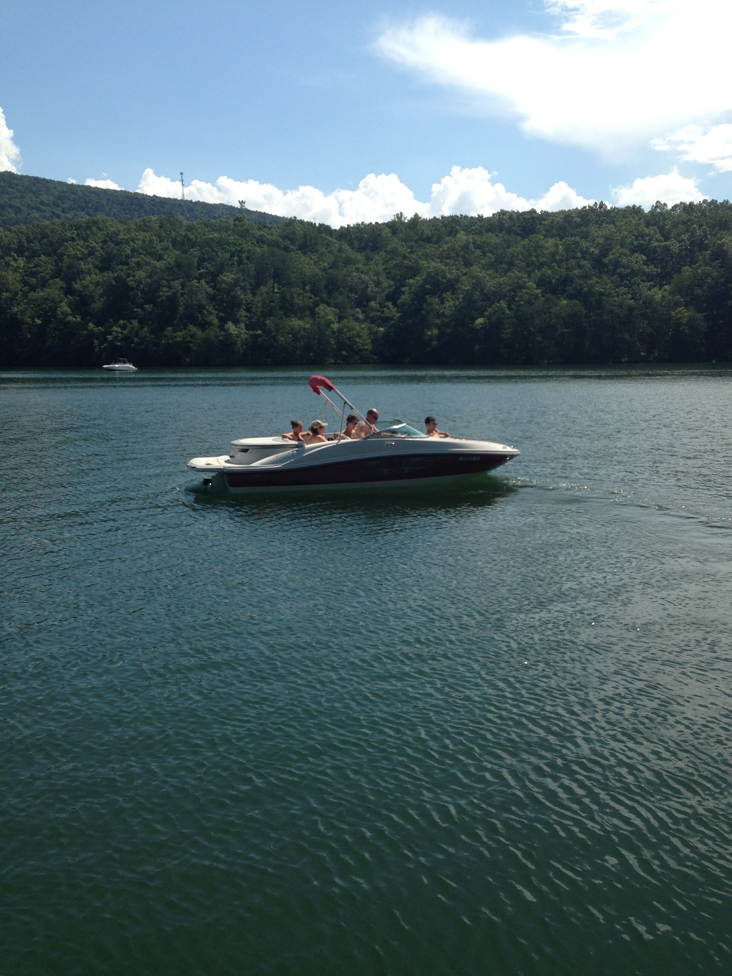 Un barco en un lago tranquilo con una colina boscosa al fondo.