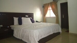A hotel room with a large bed, a nightstand, a telephone, and a window with curtains. - Hotel Codial Exclusive (Enugu)