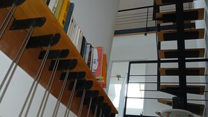 Un intérieur moderne avec un plafond en pente, une bibliothèque en bois et un fauteuil suspendu original.