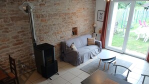Un salon chaleureux avec un mur en pierre, un canapé, une table et un poêle à bois.