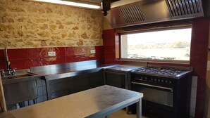 A kitchen with a gas stove, oven, and a window with a view of the outdoors.
