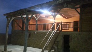 A wooden building with a balcony, a staircase, and a ladder.