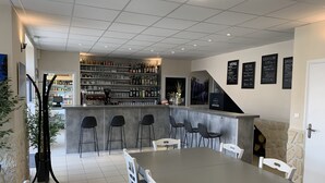 Ein Restaurant mit Barbereich, verschiedenen Sitzmöglichkeiten wie Barhocker und Tische sowie einer Speisekarte an der Wand.