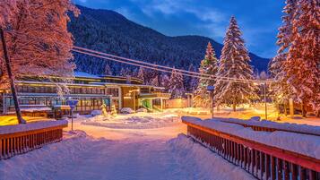 A snow-covered outdoor area with a building featuring large windows and a covered walkway.