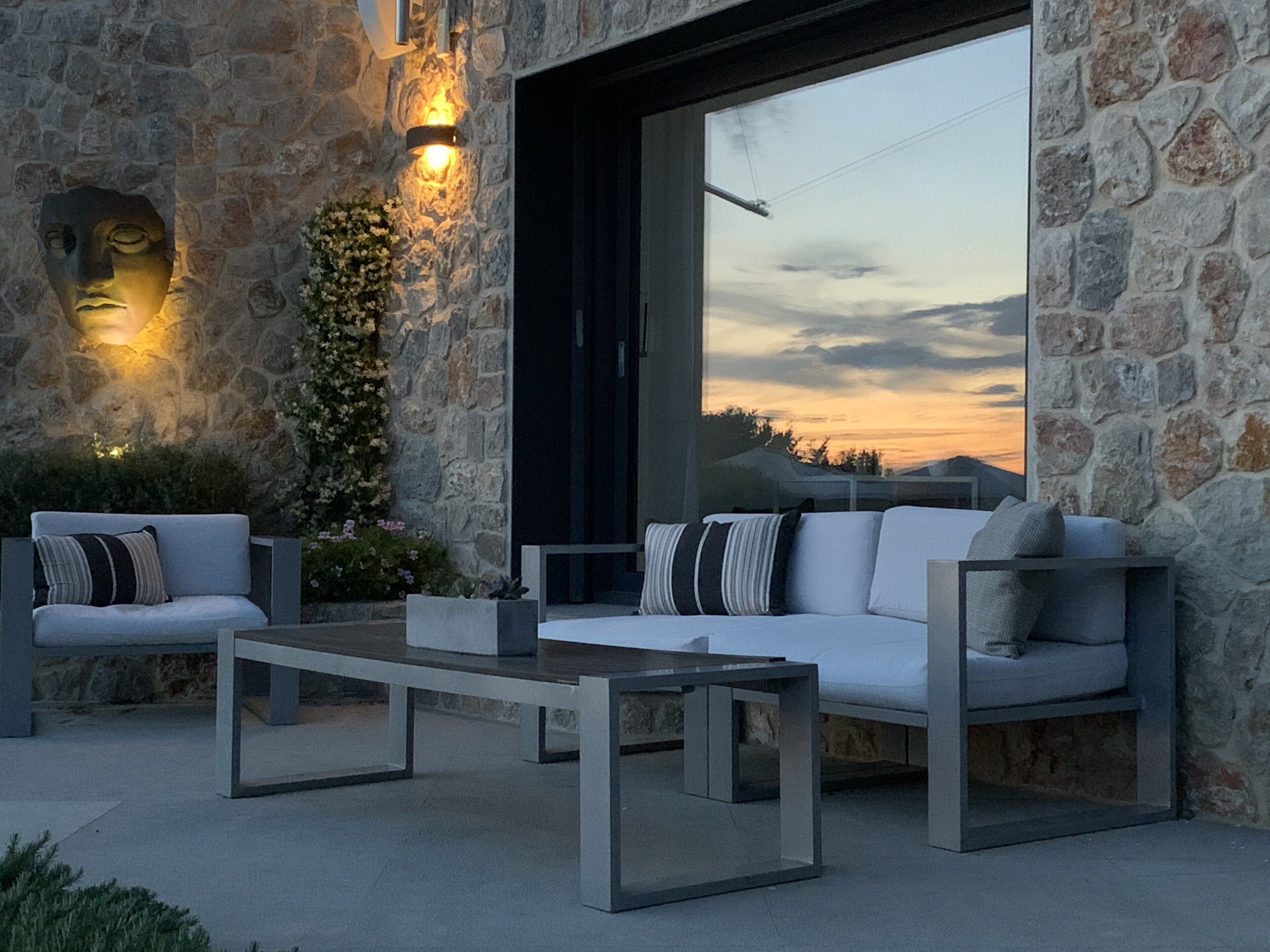 Un área de estar moderna al aire libre con pared de piedra, sofá y mesa de centro.