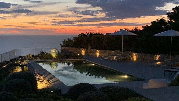 A swimming pool with a view of the ocean at sunset, surrounded by lounge chairs and umbrellas. - STUNNING LUXURY HOME WITH SEA, MOUNTAIN & SUNSET VIEWS. Private pool & terraces (Valldemossa, Mallorca)