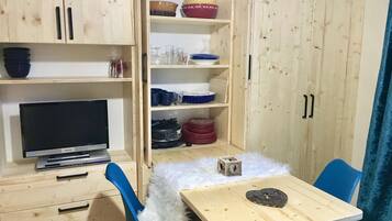 A compact room with a wooden cabinet, a television, a small table with a heart-shaped object, and a blue chair.