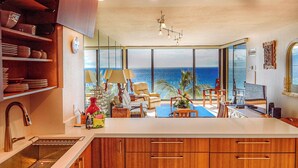 Una cocina moderna con una isla grande, armarios de madera y vista al océano.