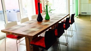 Un coin repas avec une table en bois, des chaises noires dotées de coussins rouges et deux vases ornés de fleurs.