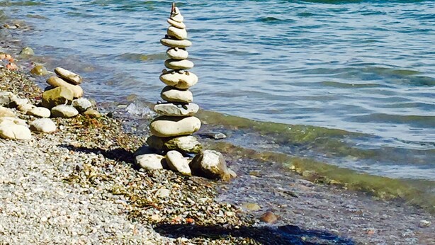 Une rivière avec un cairn de pierres au premier plan et un pont en arrière-plan.