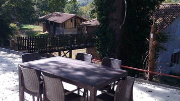 Un espace de restauration en plein air, avec une table et des chaises, entouré d’arbres et d’une clôture en bois.