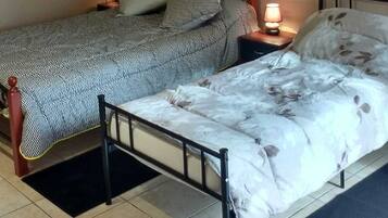 Un dormitorio con dos camas, una mesita de noche con lámpara y cabecera de madera.