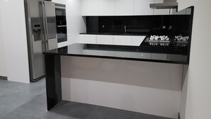 Eine moderne Küche mit einem Edelstahlkühlschrank, einer schwarzen Arbeitsplatte und weißen Schränken.