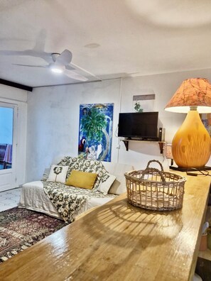 A living room with a sofa, a TV, a lamp, and a painting on the wall. - Dream apartment rocked by the trade winds  (SAINT FRANCOIS)