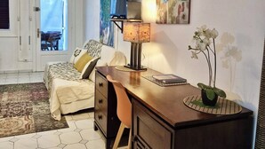 Une chambre à coucher avec un lit, un bureau, une chaise et une œuvre d’art accrochée au mur.