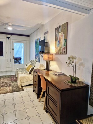 A bedroom with a bed, desk, chair, and artwork on the wall.
