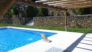 A swimming pool with a stone wall and wooden pergola overhead. - Casa Rural Los Morales, private pool, free WiFi, BBQ, 5km from Ronda. (Ronda)