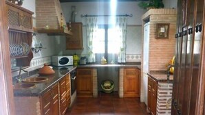 A kitchen with wooden cabinets, a tiled floor, and a window with curtains. - Casa Rural Los Morales, private pool, free WiFi, BBQ, 5km from Ronda. (Ronda)