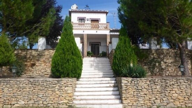 A two-story house with a stone staircase leading to the entrance, surrounded by stone walls and tall trees. - Casa Rural Los Morales, private pool, free WiFi, BBQ, 5km from Ronda. (Ronda)