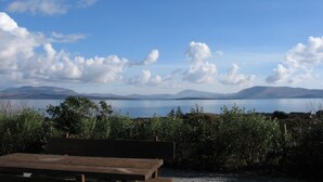 Eine hölzerne Bank mit Blick auf einen See, im Hintergrund Berge.