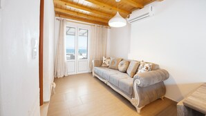 A living room with a beige sofa, wooden ceiling, and a view through a glass door.