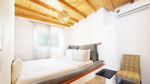 A bedroom with a bed, a chair, a small table, and a ceiling fan.
