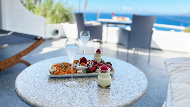 A round table with a plate of dried fruits, two glasses of a clear liquid, and a small jar of a white creamy substance.