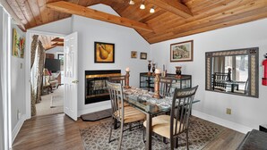 A dining area with a glass table, chairs, and a fireplace.
