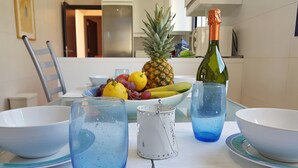 A dining table with a fruit bowl, two glasses of blue liquid, a bottle of champagne, and a small pitcher. - VILLA SA CALETA:  6 beds, 5 baths  Front line Villa In Es Forti, Cala d´Or (Santanyí)