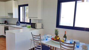 A modern kitchen with white cabinets, a built-in microwave, and a dining area with a table set for two. - VILLA SA CALETA:  6 beds, 5 baths  Front line Villa In Es Forti, Cala d´Or (Santanyí)