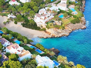 An aerial view of a coastal residential area with houses, a beach, and a clear blue sea. - VILLA SA CALETA: 6 beds, 5 baths Front line Villa In Es Forti, Cala d´Or (Santanyí)