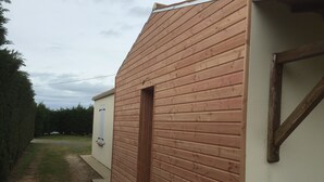 A building with a wooden exterior and a small door. - House near La Cotinière -WIFI -heated pool -classified 4* Charente Tourisme (Saint-Pierre-d'Oléron)